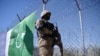 FILE - A Pakistani soldier stands guard next to a fence along Pakistan's border with Afghanistan's Paktika province, in Angoor Adda, in Pakistan's South Waziristan tribal agency, Oct. 18, 2017.
