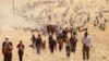 FILE - Displaced minority Yazidis, fleeing violence from forces loyal to the Islamic State in Sinjar town, walk toward the Syrian border, on the outskirts of Sinjar mountain, near Elierbeh of Al-Hasakah Governorate, Aug. 10, 2014. 