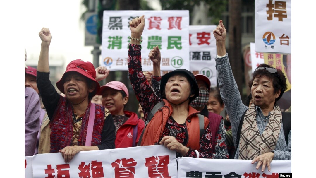 FILE - Activists shout during a protest against trade agreement with China in front of the Council of Agriculture in Taipei, Taiwan, January 4, 2016. The placards read, "Refuse trade agreement." "Trade agreement kill farmers."