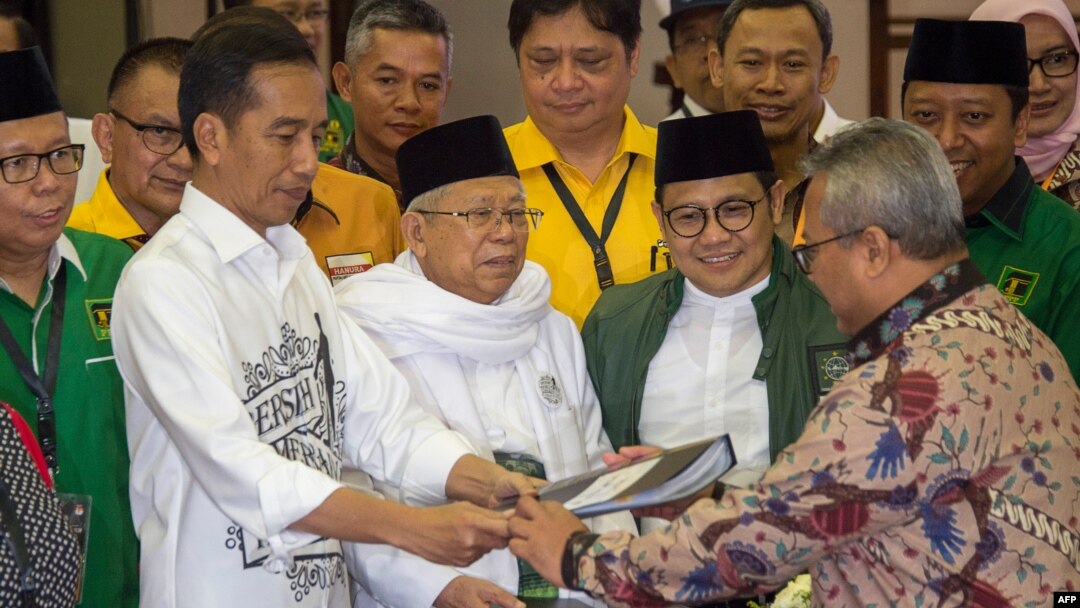 Indonesia's President Joko Widodo, front left, and the head of Indonesian Ulema Council Maruf Amin, center, submit their documents to election commission officials in Jakarta, Aug. 10, 2018, during their registration for the 2019 presidential election as president and vice president candidates.
