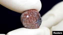 A conservator shows a 2,700-year-old clay seal impression which archaeologists from the Israel Antiquities Authority say belonged to a biblical governor of Jerusalem and was unearthed in excavations in the Western Wall plaza in Jerusalem's Old City January 1, 2018. REUTERS/Nir Elias.