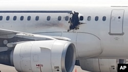 FILE - A gaping hole is visible in the side of a plane operated by Daallo Airlines as it sits on the runway of the airport in Mogadishu, Somalia, Feb. 2, 2016. 
