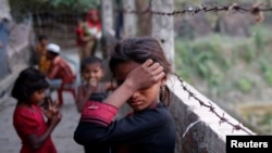 FILE - A Rohingya refugee girl wipes her eyes as she cries at Leda Unregistered Refugee Camp in Teknaf, Bangladesh, Feb. 15, 2017.