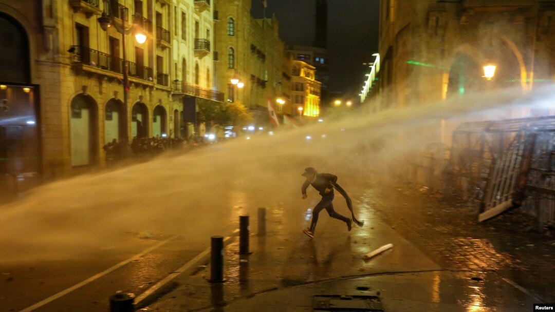 FILE - A demonstrator is hit by a water cannon during a protest against a ruling elite accused of steering Lebanon towards economic crisis, in Beirut, Lebanon, Jan. 19, 2020.