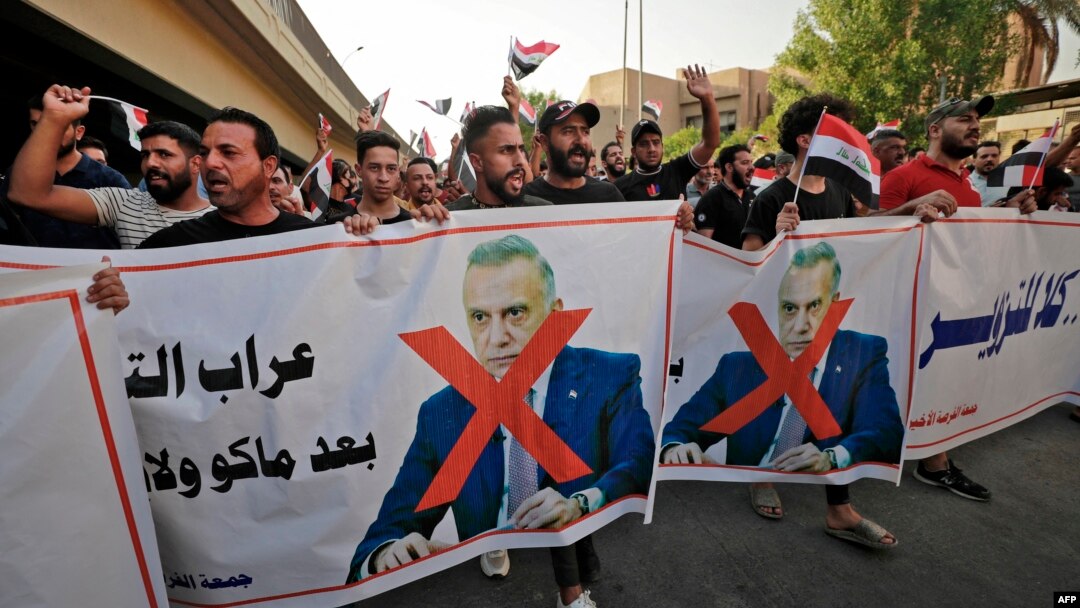 Iraqi demonstrators lift banners against Prime Minister Mustafa Al-Kadhimi during a protest rejecting last month's election result, near an entrance to the Green Zone in Baghdad, November 5, 2021.