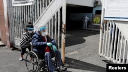 A woman takes her relative showing symptoms of the coronavirus disease (COVID-19) to the emergency area of the San Juan de Dios hospital, in Guatemala City, Guatemala, July 15, 2020. REUTERS/Luis Echeverria