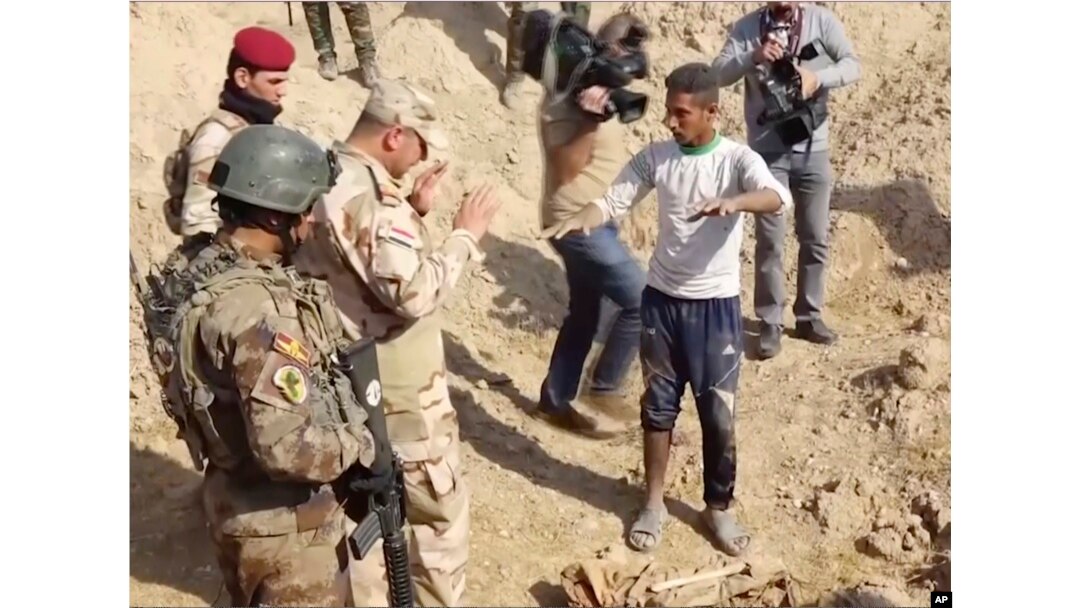 Iraqi security forces speak to shepherd Khalaf Luhaibi next to bones on the ground at an abandoned base near the northern town of Hawija, Iraq, Nov. 22, 2017.