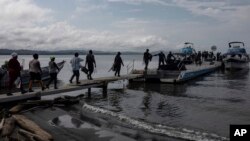 ARCHIVO - Migrantes abordan barcos hacia el Tapón del Darién, en Necoclí, Colombia, 7 de octubre de 2023. 
