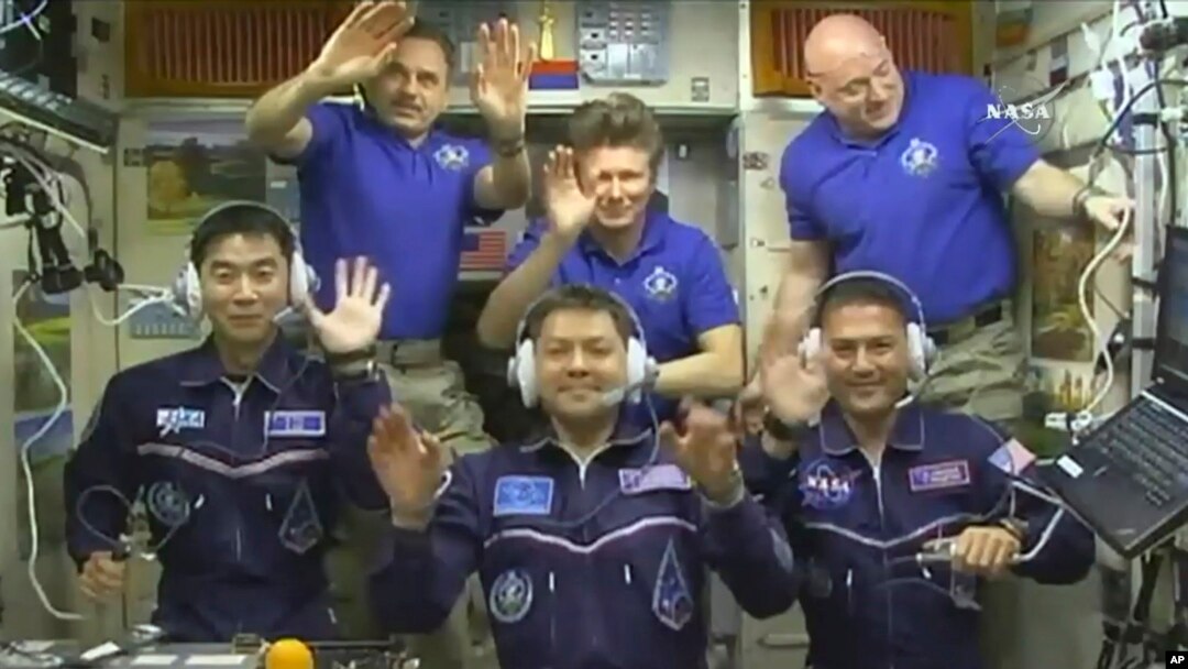 FILE - In this image taken from video from NASA, astronauts, front row from left, Kimiya Yui, of Japan, Oleg Kononenko, of Russia, and Kjell Lindgren, of the United States, wave after they boarded the International Space Station, July 23, 2015. The three crew members boarded a Russian Soyuz capsule on Friday for an express ride back to Earth.