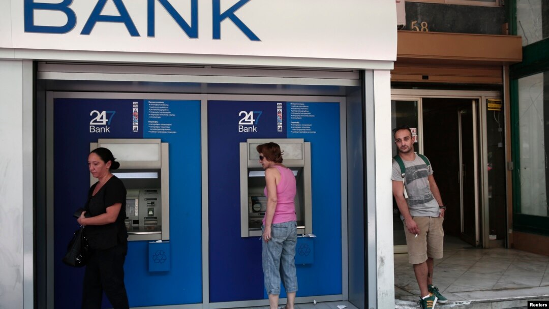 希臘人8月12日在雅典一家銀行外使用提款機。