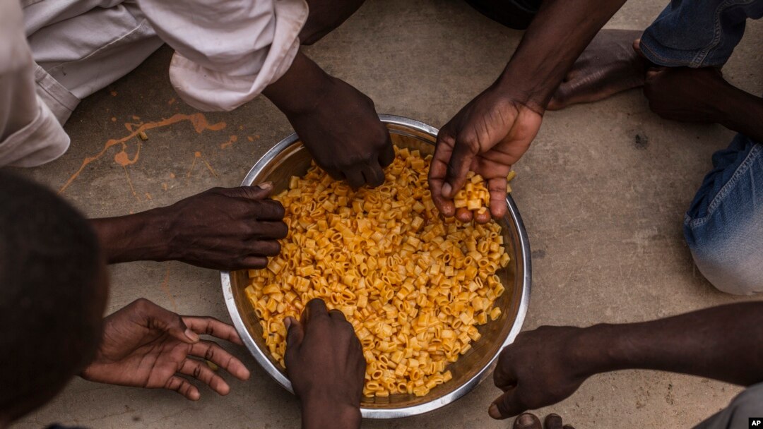 Migrants share a bowl of pasta during their lunch at the courtyard of a detention center for migrants, in the village of Karareem, around 50 kilometers from Misrata, Libya, Sept. 25, 2016. Libya is an important transit and destination country for migrants who arrive seeking employment or a path to Europe.