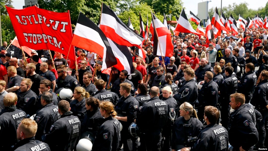 FILE - Riot police watch as far-right supporters take part in anti-refugee rally in Dortmund, Germany, June 4, 2016. The placard in front reads "Stop the flood of asylum seekers."