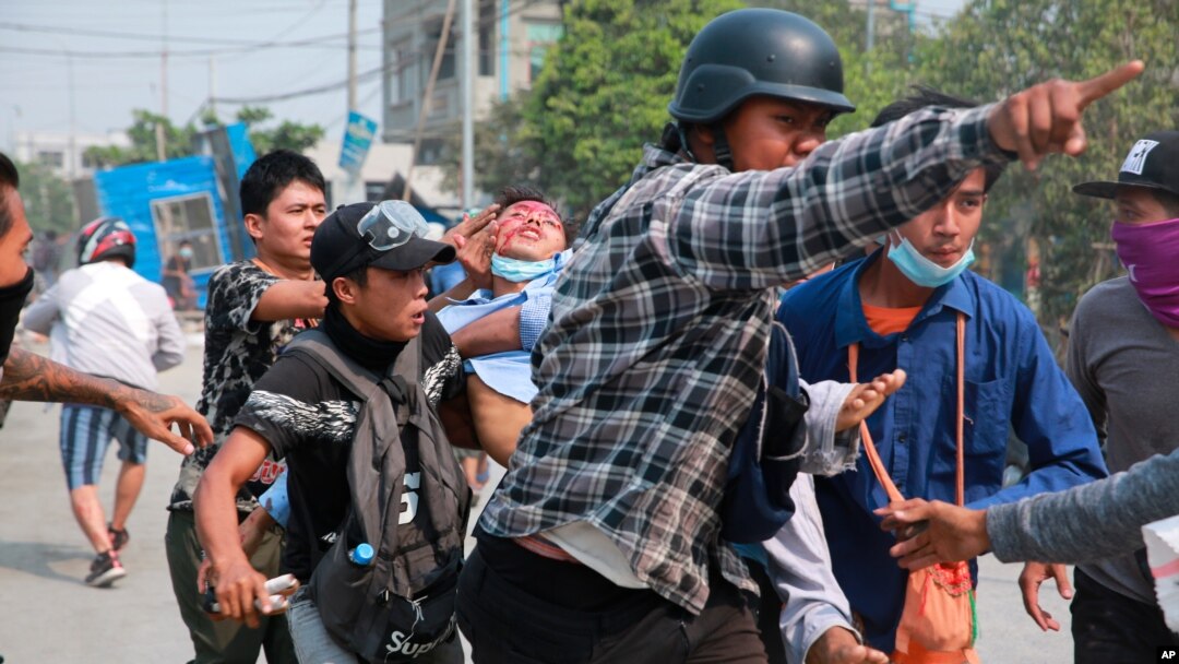 A man with a head injury is carried by fellow demonstrators during an anti-coup protest in Mandalay, Myanmar, March 22, 2021.