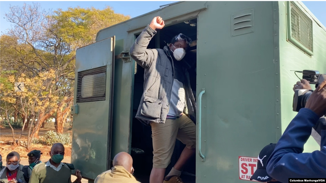 Defiant journalist Hopewell Chin'ono raises his fist to colleagues, relatives and friends while getting into a waiting prison vehicle July 23, 2020, outside Harare Magistrates Court after saying he would not be 'bowed' from talking about corruption becau