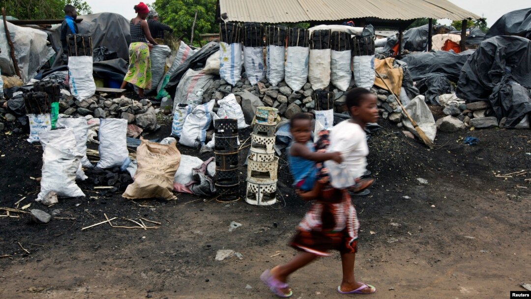 Children walk past charcoal sellers in Kitwe, Zambia, Jan. 17, 2015. 