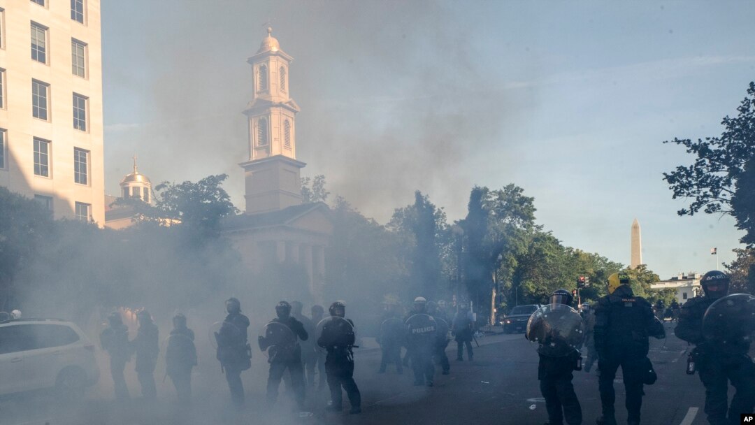 FILE - Tear gas floats in the air as a line of police move demonstrators away from St. John's Church at Lafayette Park near the White House, as they gather to protest the death of George Floyd, June 1, 2020, in Washington. 