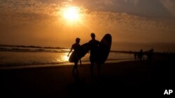 La silueta de dos surfistas se aprecia en esta foto de un atardecer en la playa Venice, de Los Angeles, el 16 de junio del 2021.