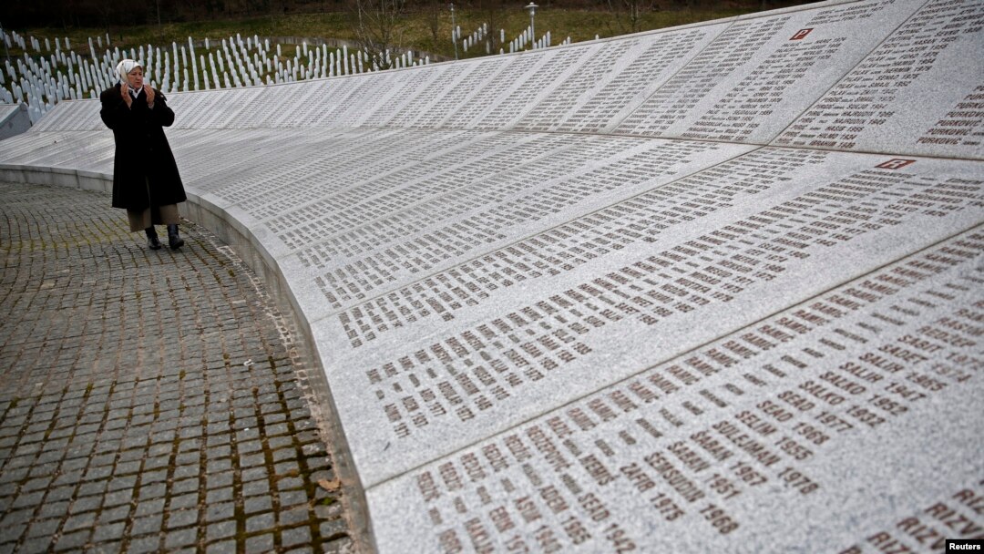 FILE - Fadila Efendic prays near memorial plaques at the Potocari genocide memorial center near Srebrenica, March 18, 2015. 