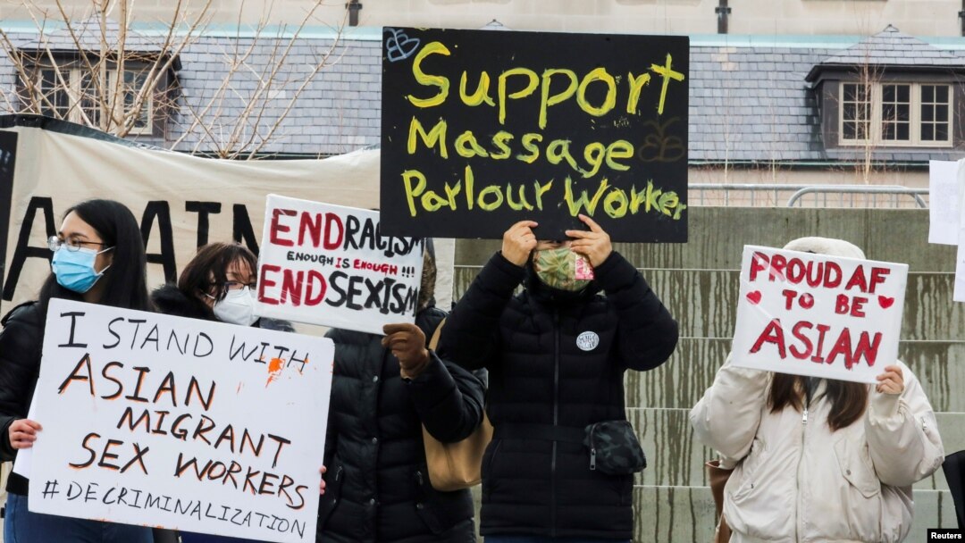 FILE - People hold placards as they gather to protest anti-Asian hate crimes and vandalism, outside City Hall in Toronto, Ontario, Canada, March 28, 2021. 
