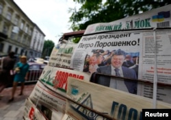 FILE - People walk past a news stand a day after the Ukrainian presidential election in the western Ukrainian city of Lviv May 26, 2014.