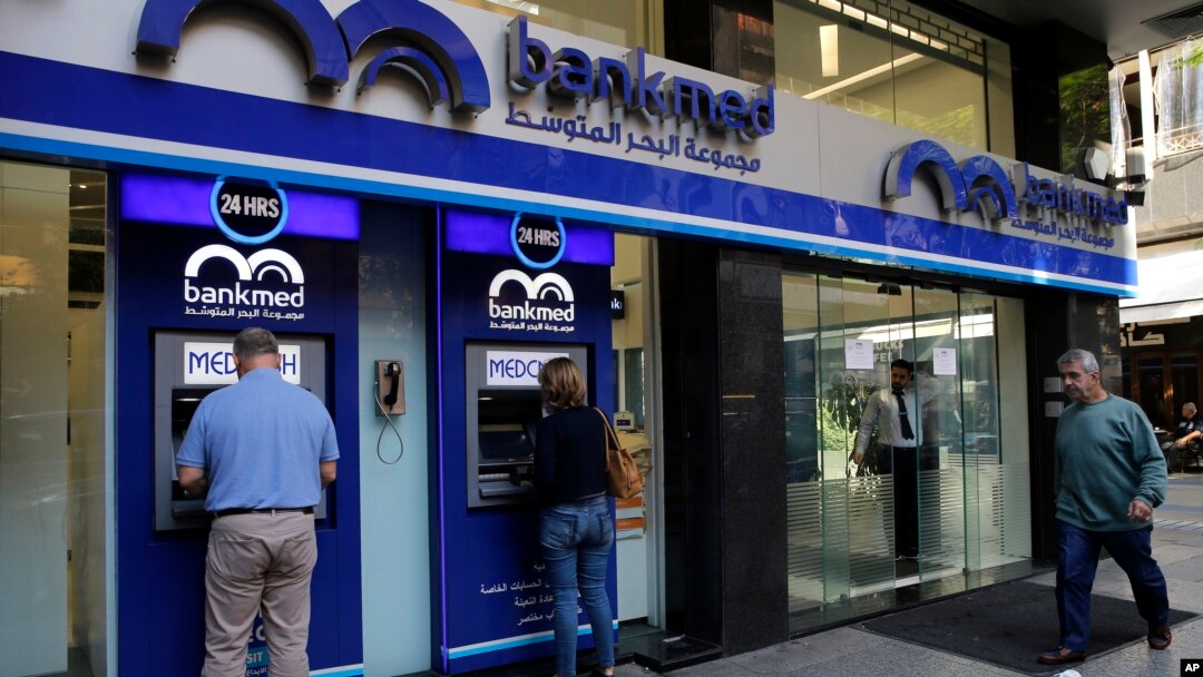 FILE - People use an ATM outside a bank, in Beirut, Lebanon, Nov. 20, 2019. 