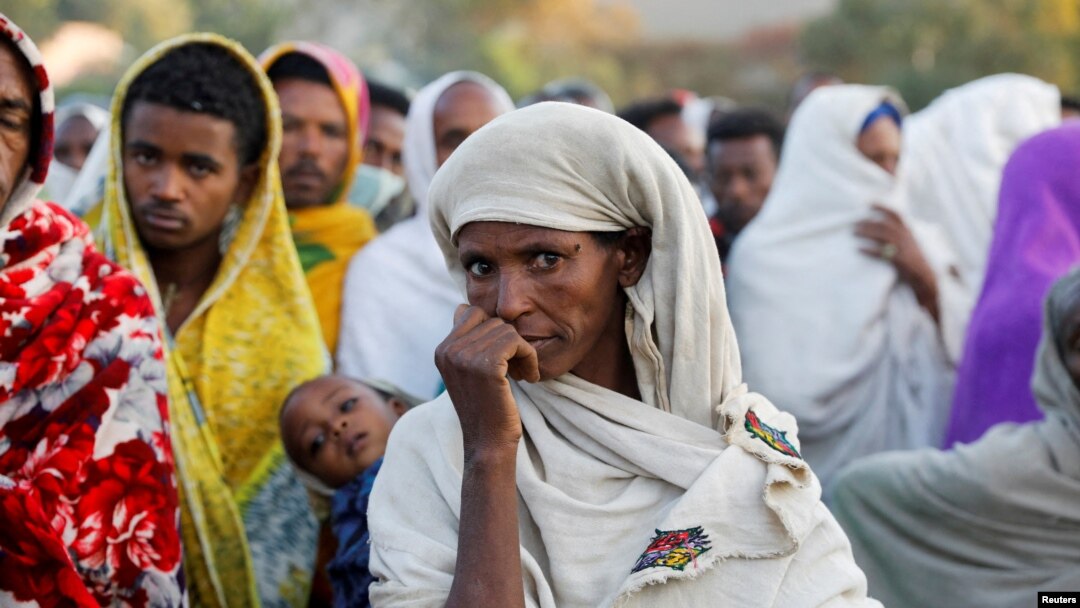 FILE - A woman stands in line with others to receive food donations at a school, which was turned into a temporary shelter for people displaced by conflict, in the town of Shire, in Ethiopia's Tigray region, March 15, 2021.