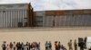 FILE - Members of the Border Patrol and U.S. military talk with migrants who illegally crossed the border between Mexico and the U.S. to request political asylum, as seen from Ciudad Juarez, Mexico, July 6, 2019. 