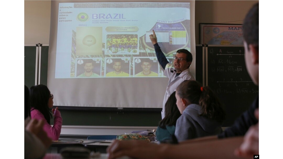 FILE - Ari Mascarenhas teaches students Portuguese using the World Cup sticker book, in Sao Paulo, Brazil, May 21, 2018.