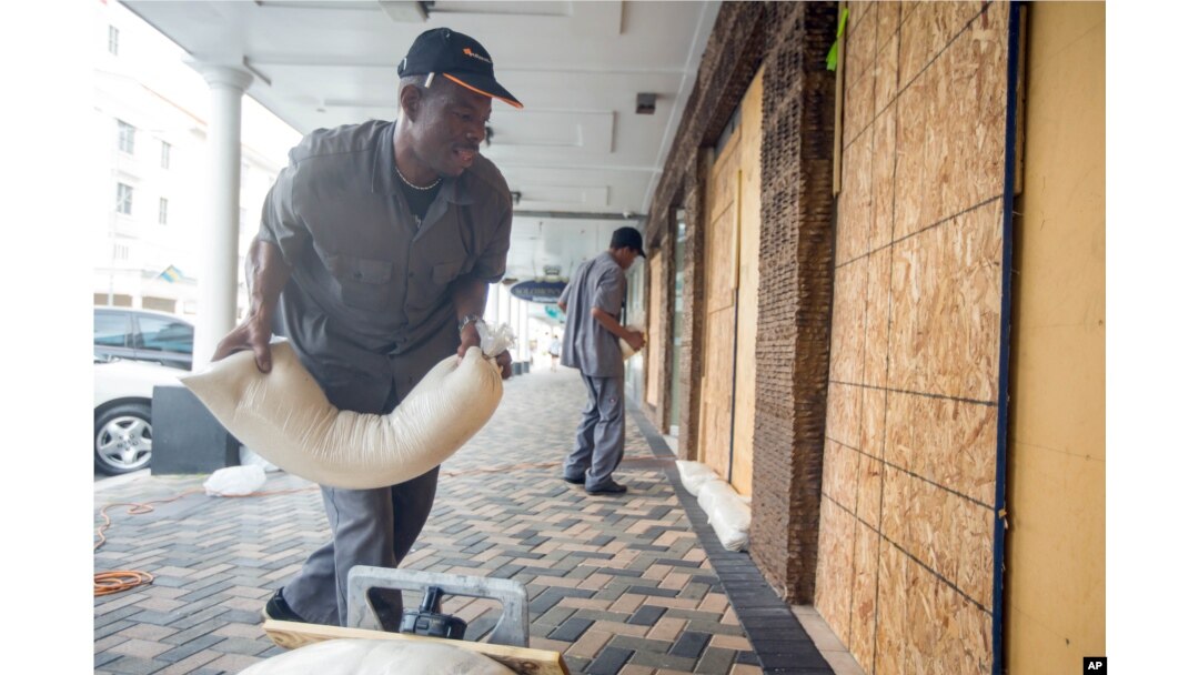 Perry Williams, 47, left, and Alaric Nixon, 28, place sandbags on the storefront of Diamond's International store, in preparation for the arrival of hurricane Joaquin in Nassau, Bahamas, Oct. 1, 2015.