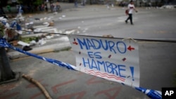 Un cartel en rechazo al presidente Nicolás Maduro es desplegado en una calle de Caracas, Venezuela, el miércoles, 26 de julio de 2017, como parte de una barricada en el paro de 48 horas convocado por la oposición.
