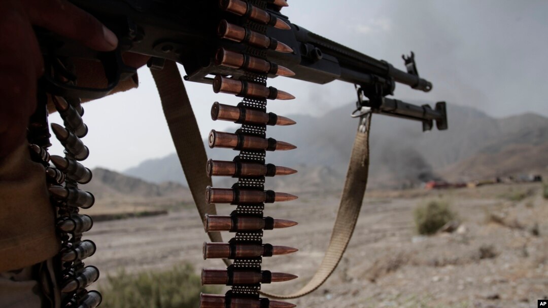 FILE - An Afghan policeman stands guard near burning NATO supply trucks following an attack by militants on a U.S. base in the Torkham area near the Pakistan-Afghanistan border in Jalalabad province east of Kabul, Afghanistan, Sept. 2, 2013.