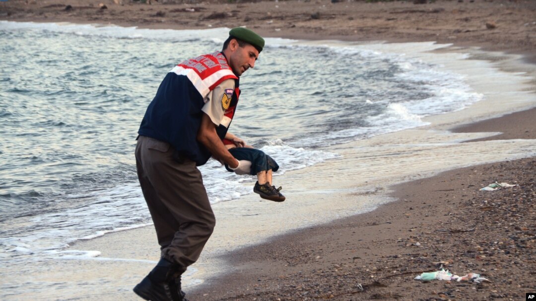 A paramilitary police officer carries the lifeless body of a migrant boy near the Turkish resort of Bodrum early Wednesday, Sept. 2, 2015. (AP Photo/DHA)