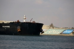 A cargo ship sails through the town of Ismailia, Egypt, March 30, 2021 as traffic resumed through the Suez canal after it was blocked by a massive ship that had been stuck sideways for nearly a week.