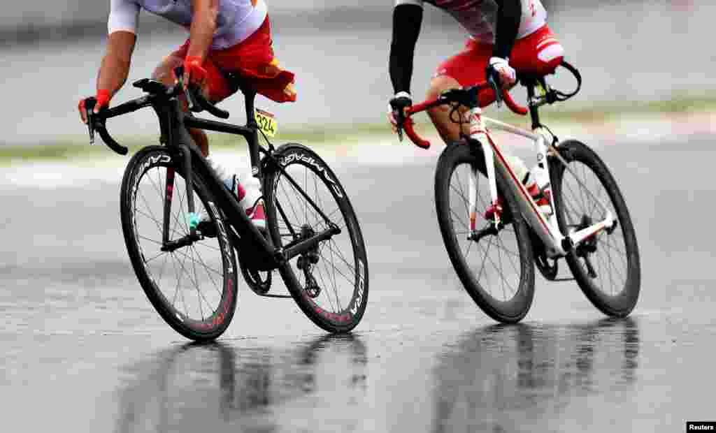 Guihua Liang of China and Shota Kawamoto of Japan compete in the men's cycling road C1-3 at the Fuji International Speedway during the Tokyo 2020 Paralympic Games in Oyama, Japan.