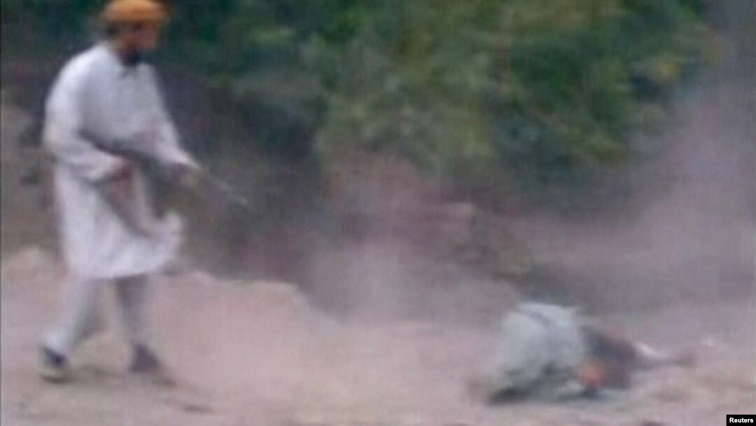 This still image taken from undated video footage depicts a man Afghan officials identified as a member of the Taliban firing his rifle at a woman accused of adultery during her execution in a village outside Kabul, Afghanistan.