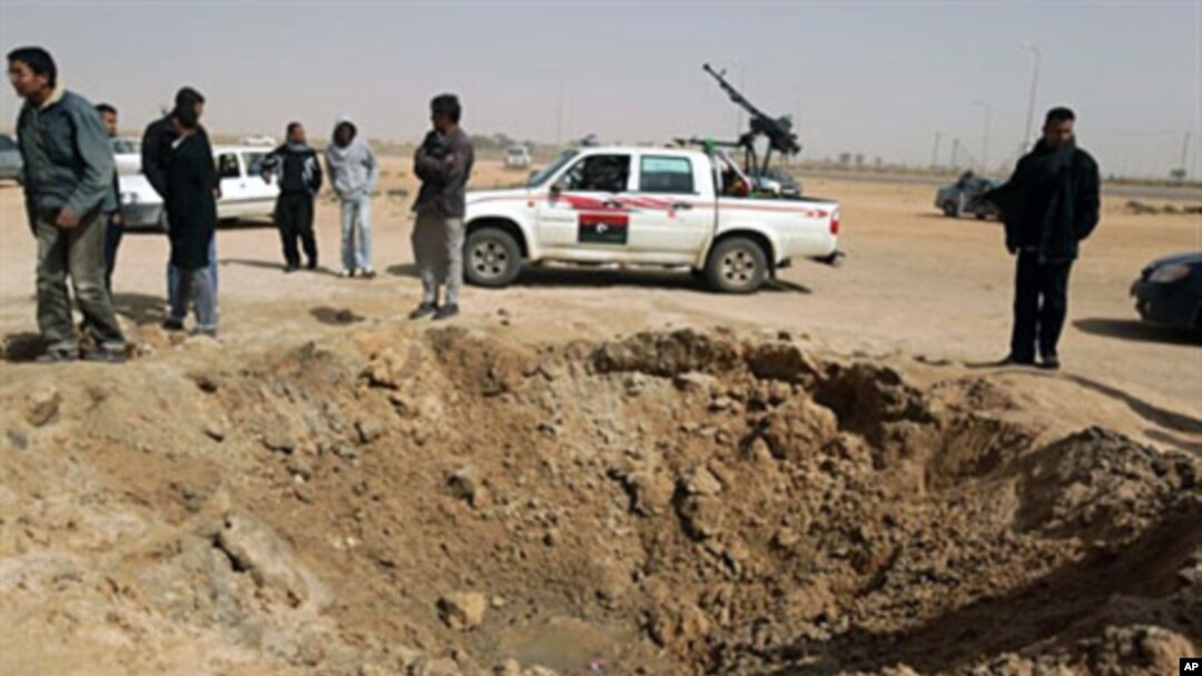 Libyan rebels inspect a crater caused by a bomb dropped by a plane in Ajdabiya on Mar 14 2011 as Libyan strongman Moamer Kadhafi's forces shelled rebel positions