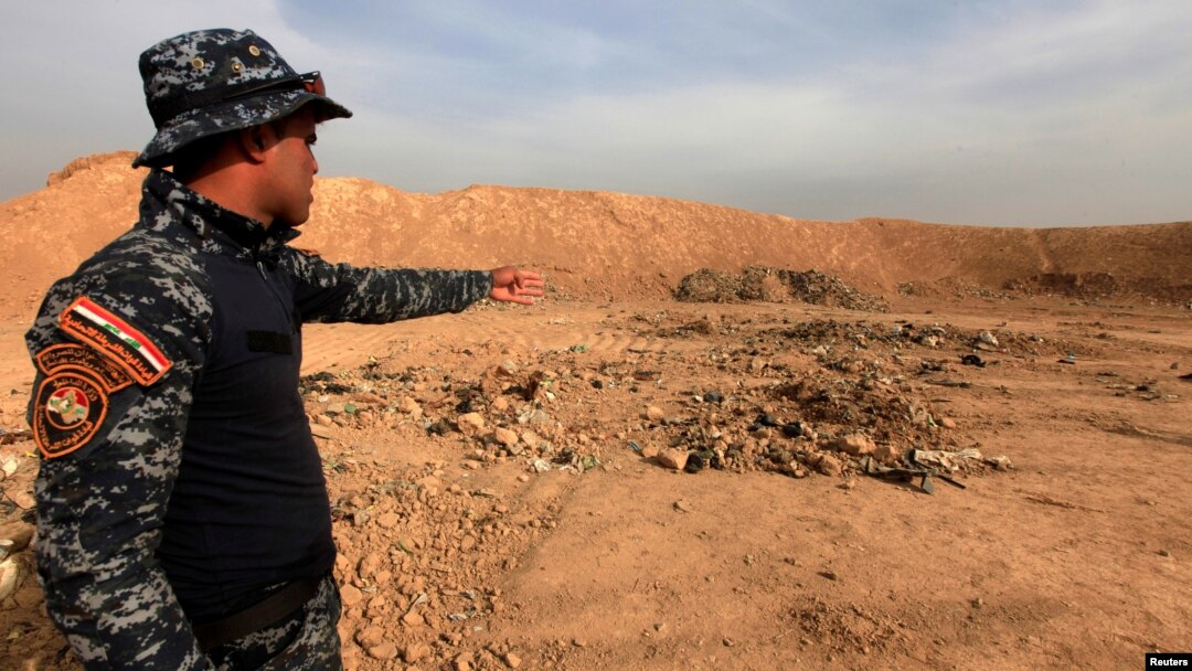 A member of Iraqi security forces gestures toward a mass grave in the town of Hammam al-Alil, which was seized from Islamic State, Nov. 9, 2016.