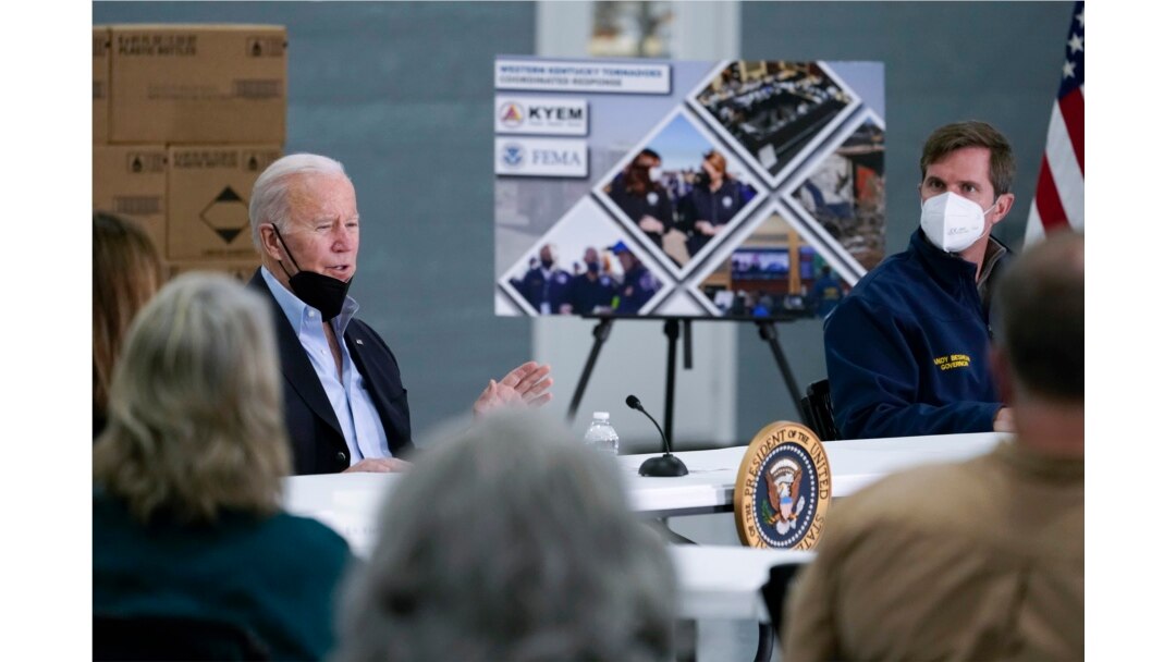 Kentucky Gov. Andy Beshear, right, listens as President Joe Biden speaks during a briefing from local leaders on the storm damage from tornadoes and extreme weather at Mayfield Graves County Airport in Mayfield, Ky., Dec. 15, 2021.