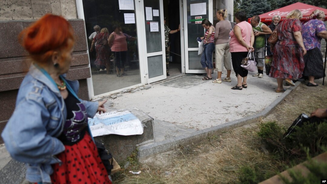 FILE - Local residents stand in line to get benefit payments outside the rebel headquarters in Donetsk, eastern Ukraine, Aug. 19, 2014. 