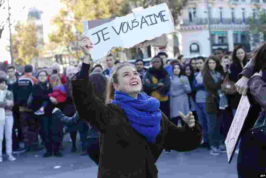 A woman holds a placard reading 'I love you' as people gather at the Place de la Republique in Paris, on Nov. 15, 2015, two days after a series of deadly attacks.