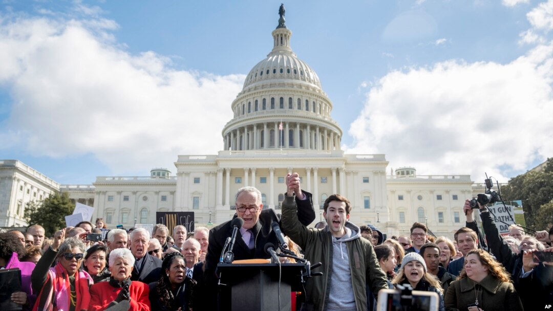 Senate Minority Leader Sen. Chuck Schumer, D-N.Y., holds hands with student activist Matt Post, right, during a student gun control advocates rally outside the Capitol Building in Washington, March 14, 2018. Students walked out of school to protest gun violence in the biggest demonstration yet of the student activism that has emerged in response to last month's massacre of 17 people at Florida's Marjory Stoneman Douglas High School. 