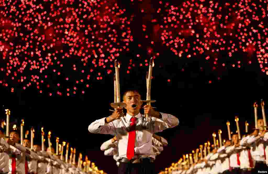 Fireworks explode over participants carrying torches during a torchlight procession during the celebration marking the 70th anniversary of North Korea's foundation in Pyongyang, North Korea.