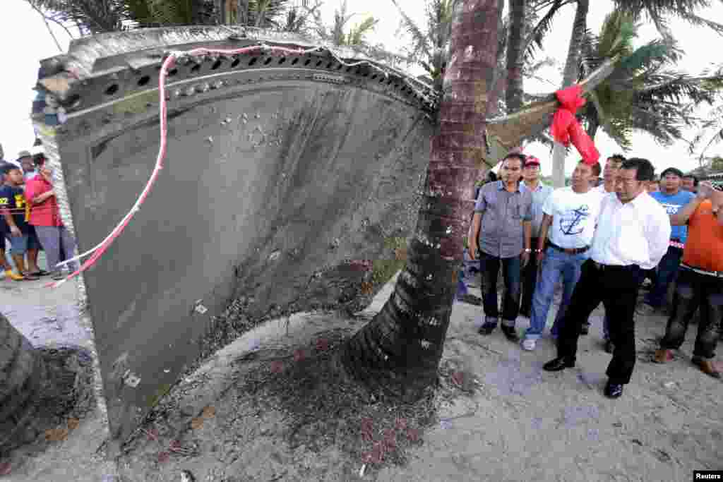 People stand next to a piece of suspected plane wreckage which has been found off the coast of southern Thailand in Nakhon Si Thammarat province, Jan. 24, 2016.