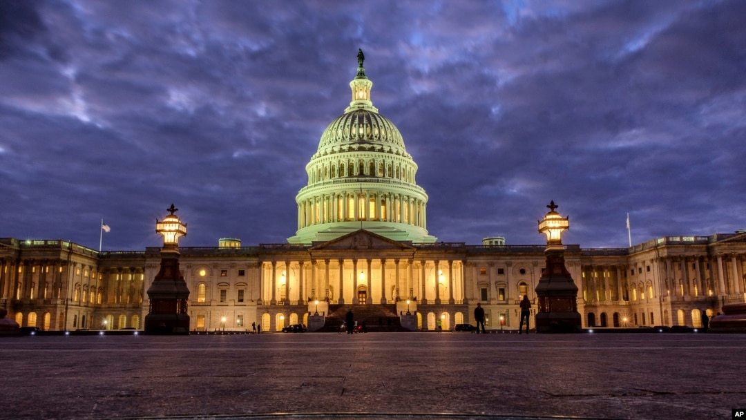 FILE - In this Jan. 21, 2018 file photo, lights shine inside the U.S. Capitol Building as night falls in Washington. 