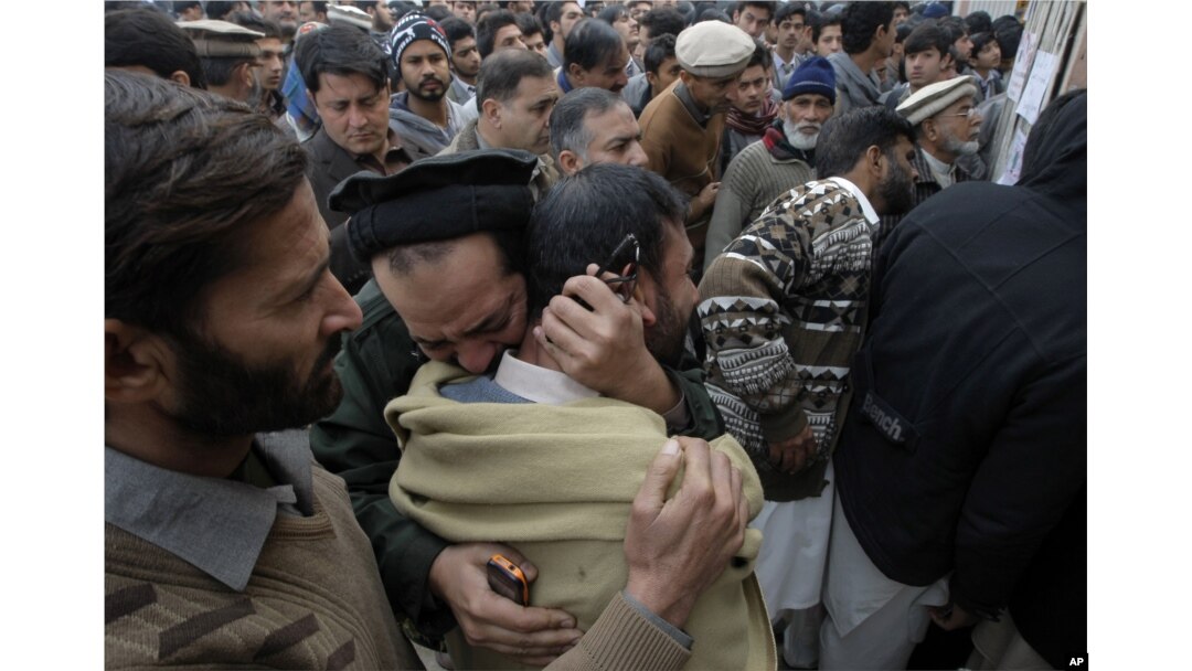 FILE - Pakistanis mourn over the death of their children at an entry gate of the Army Public School, attacked by Taliban militants, as they gather in Peshawar, Pakistan, Dec. 20, 2014.