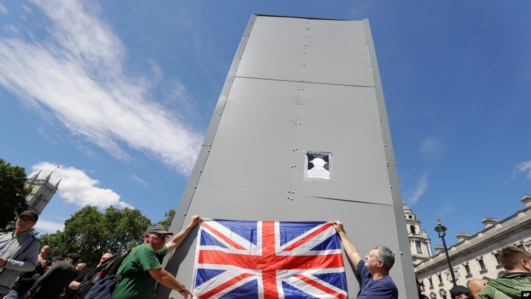 Members of far-right Football Lads Alliance hold a British flag in front of a protective covering surrounding the statue of former British Prime Minister Sir Winston Churchill in Parliament Square, central London, June 13, 2020.