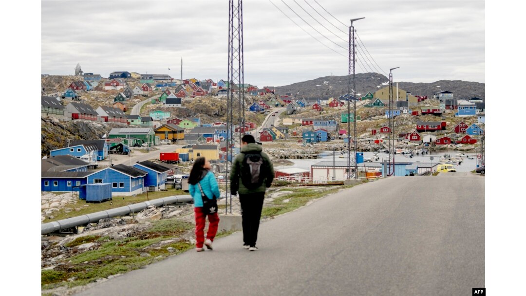 FILE - Residents walk in the town of Aasiaat, Greenland, on June 29, 2024.