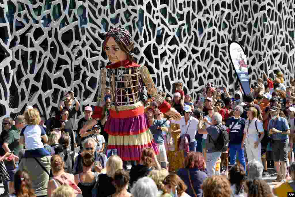 "Little Amal," a giant puppet depicting a Syrian refugee girl traveling 8,000 kilometers across Turkey and Europe, is carried along the Mucem museum in Marseille, Sept. 22, 2021, as part of "The Walk," a festival of art.