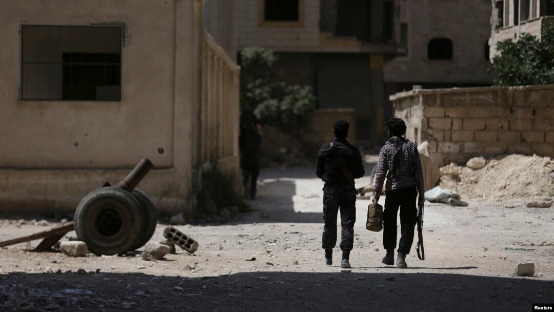 FILE - Fighters from the Free Syrian Army's Al Rahman legion walk toward their positions in Jobar, a suburb of Damascus, Syria.