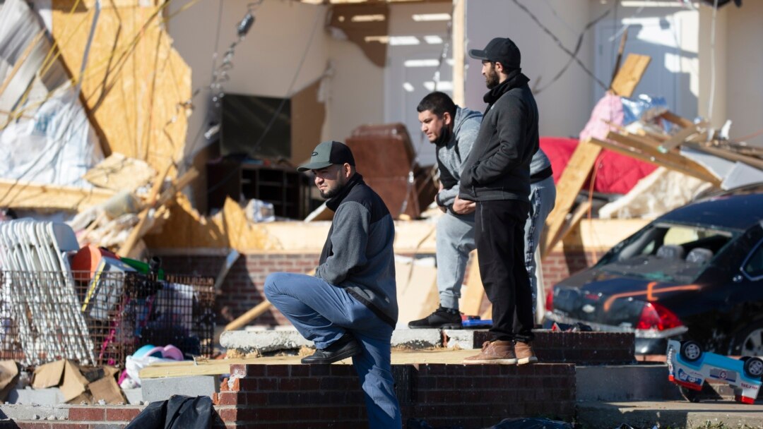 Jose Rivas, left, looks at tornado damage, Dec. 14, 2021, in Bowling Green, Ky.